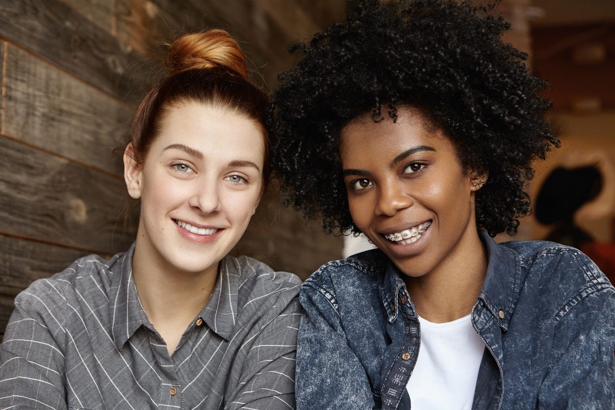 Two smiling adults, one wearing braces