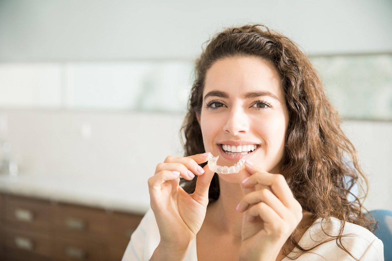 Smiling woman holding her clear retainer